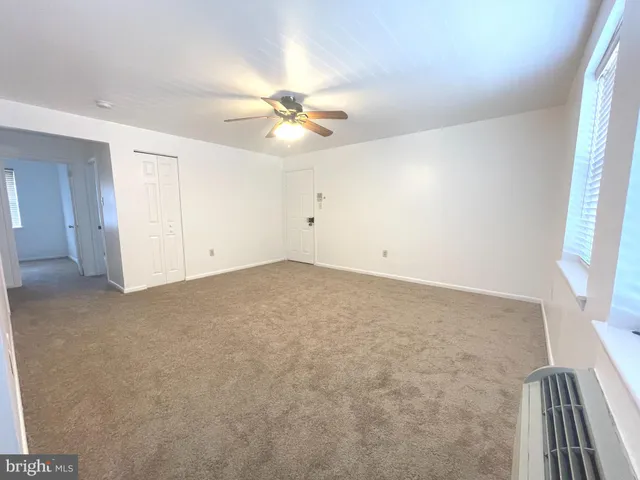 an empty room with a ceiling fan and a window