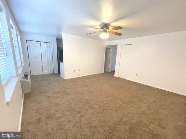 an empty room with a ceiling fan and a window