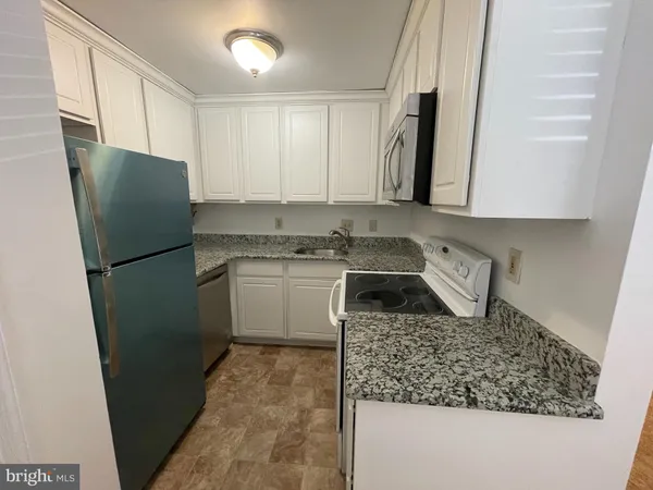 a kitchen with a sink a refrigerator and cabinets