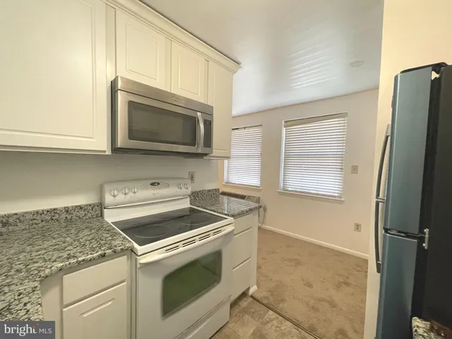 a kitchen with granite countertop cabinets stainless steel appliances and a counter space