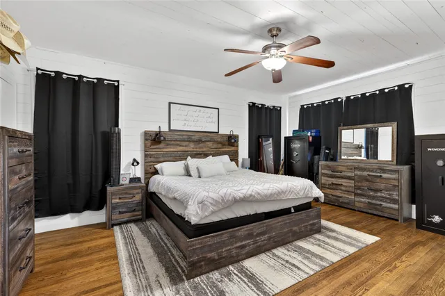 a bedroom with a large bed dresser and wooden floor
