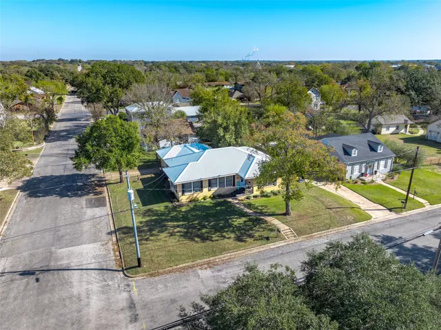 an aerial view of residential houses with outdoor space and trees
