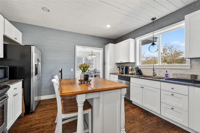 a kitchen with granite countertop a sink appliances cabinets and furniture