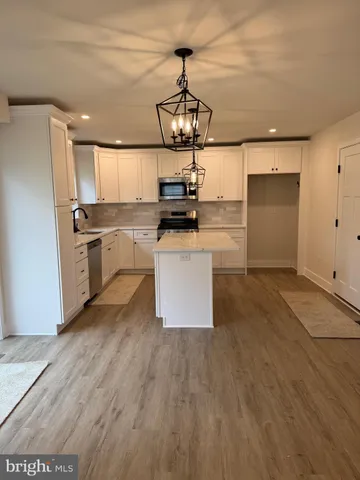 a kitchen with stainless steel appliances granite countertop a wooden floor a stove and a refrigerator