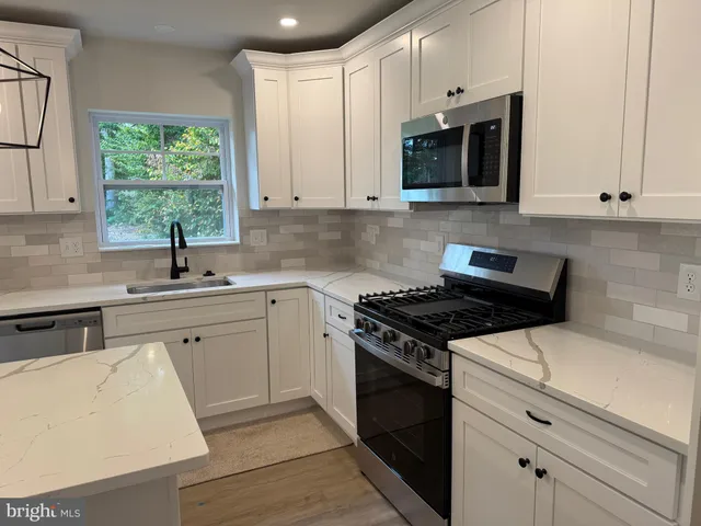 a kitchen with stainless steel appliances white cabinets and a stove top oven