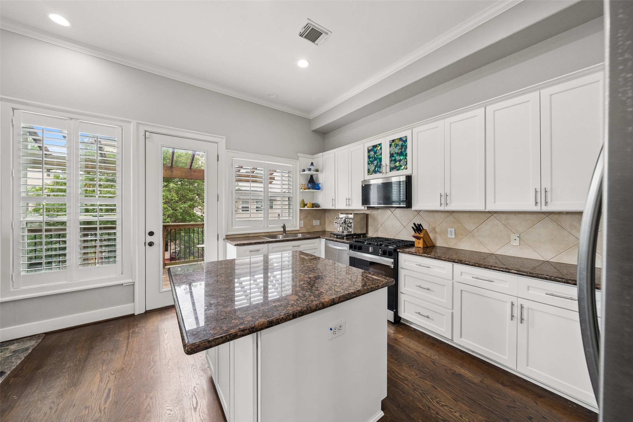 1317 Bomar Street Houston, TX 77006 - Photo 16 of 32 a kitchen with stainless steel appliances granite countertop a sink dishwasher stove and white cabinets with wooden floor