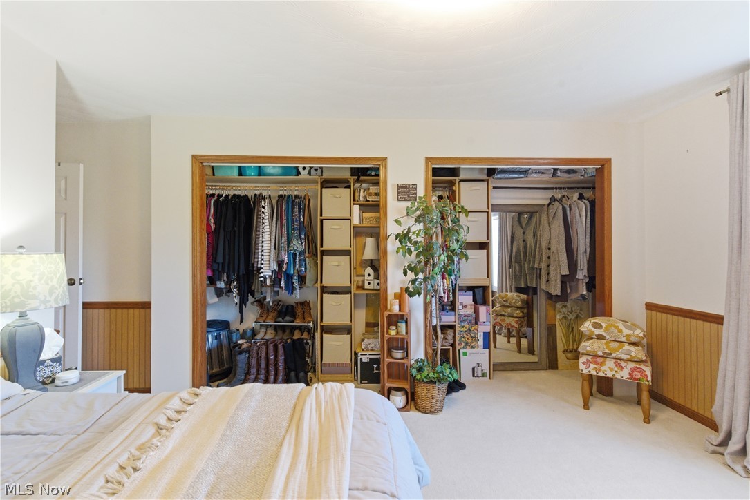 52450 Tower Road Cumberland, OH 43732 - Photo 17 of 41 Bedroom featuring a wainscoted wall, light colored carpet, multiple closets, and wood walls
