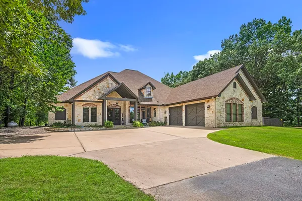 a front view of a house with a garden and trees
