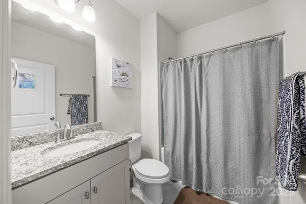 a bathroom with a granite countertop sink toilet and a mirror
