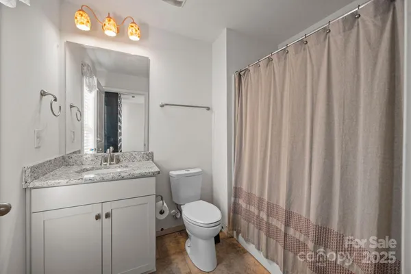 a bathroom with a granite countertop sink toilet and mirror