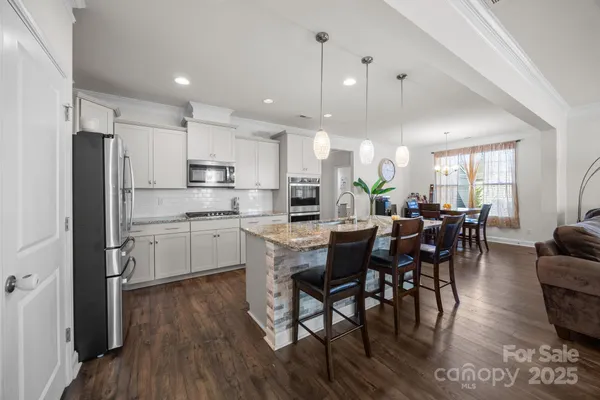 a kitchen with kitchen island granite countertop stainless steel appliances a dining table and chairs