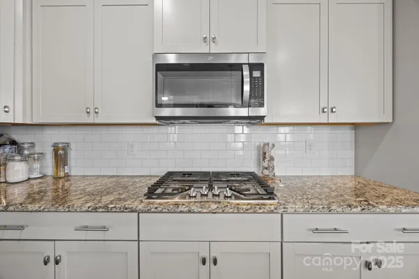 a kitchen with granite countertop white cabinets and appliances