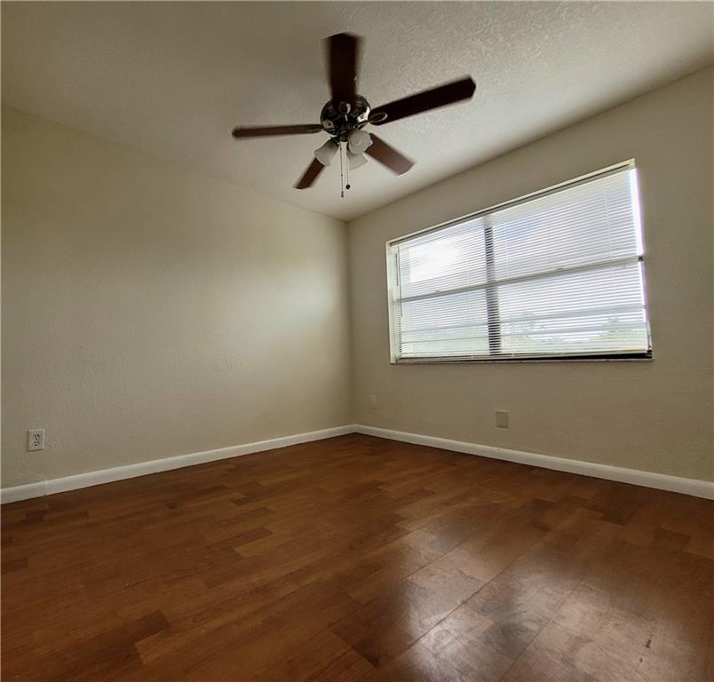 11096 Royal Palm Boulevard, Unit 11096 Coral Springs, FL 33065 - Photo 9 of 20 an empty room with wooden floor chandelier fan and windows