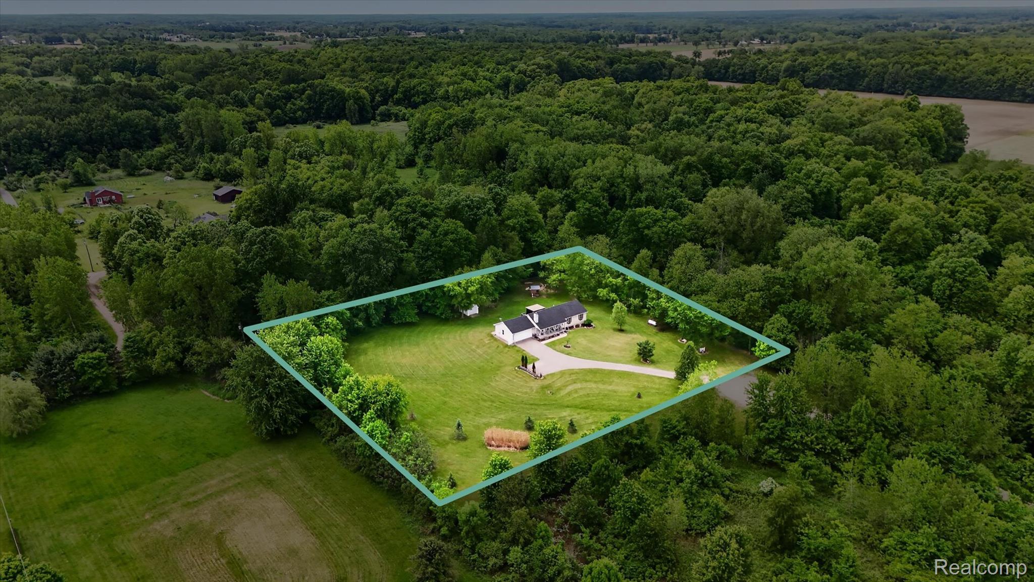 9565 Crofoot Road Fowlerville, MI 48836 - Photo 56 of 63 Aerial perspective showcasing a single-story residence with an attached garage, surrounded by expansive green space and mature trees