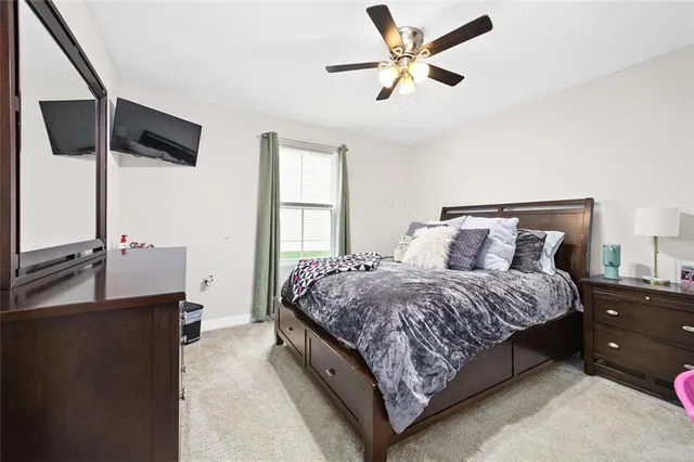 a spacious bedroom with a bed and a flat tv screen on dresser