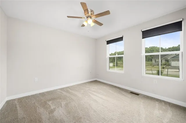 an empty room with a window and a ceiling fan