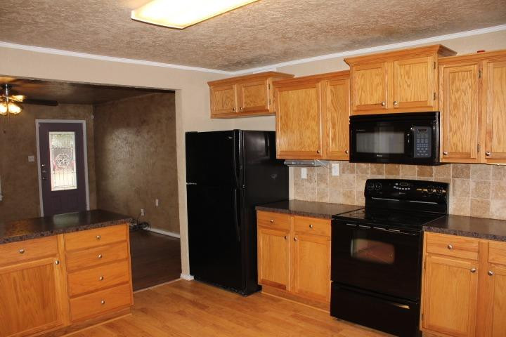 3111 30th Street Lubbock, TX 79410 - Photo 5 of 22 a kitchen with granite countertop a refrigerator stove and microwave