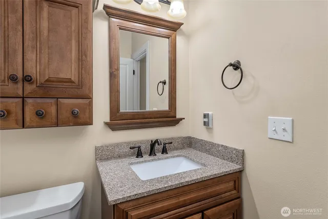 a bathroom with a granite countertop toilet sink and mirror