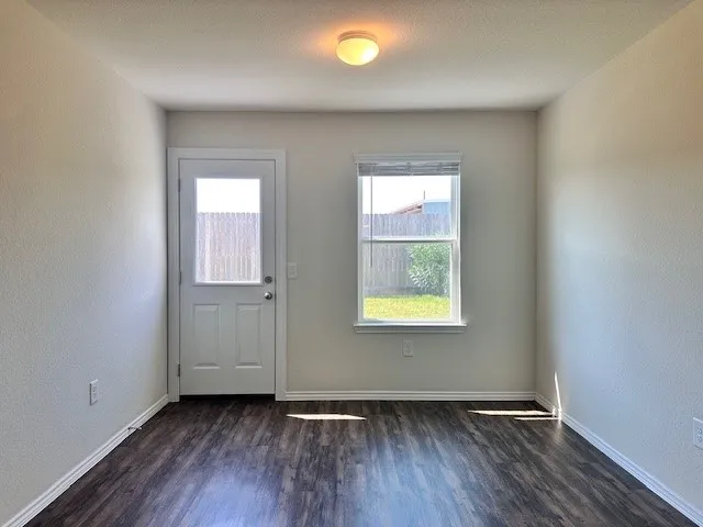 an empty room with wooden floor and windows