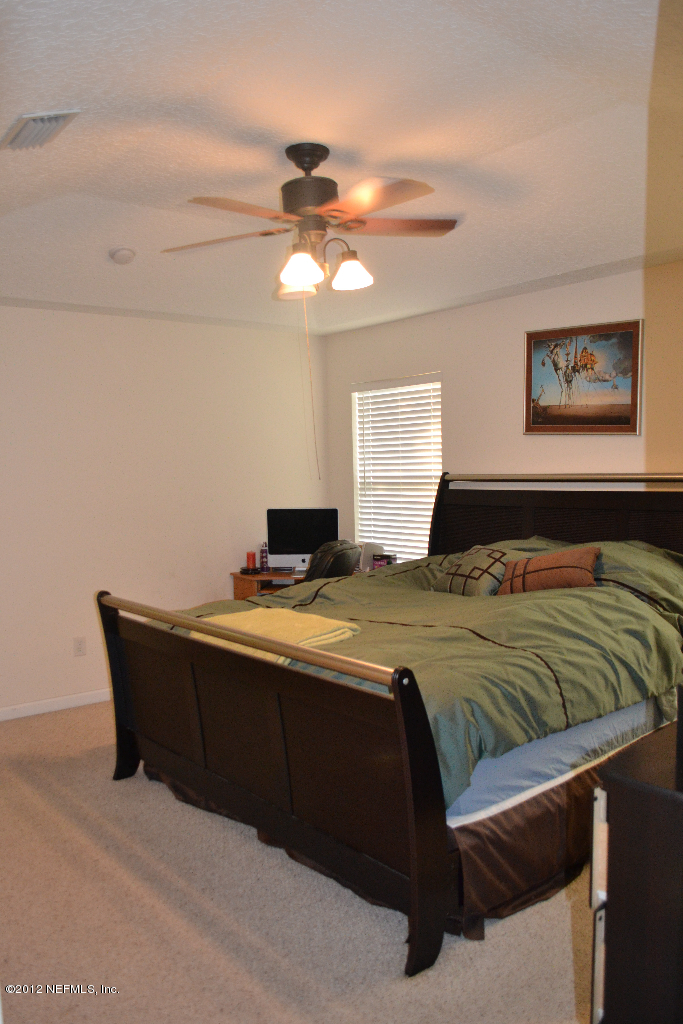 12058 Spring Ridge Drive Jacksonville, FL 32258 - Photo 5 of 9 a bedroom with a bed and a chandelier