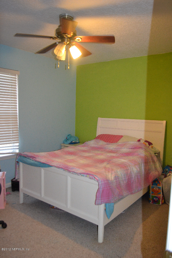 12058 Spring Ridge Drive Jacksonville, FL 32258 - Photo 6 of 9 a bedroom with a bed and a chandelier