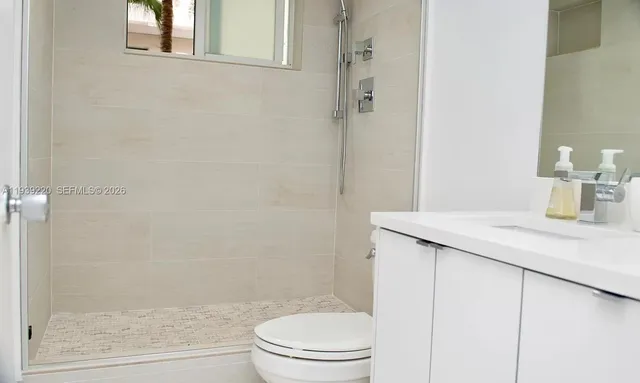 a bathroom with a granite countertop sink a toilet and shower