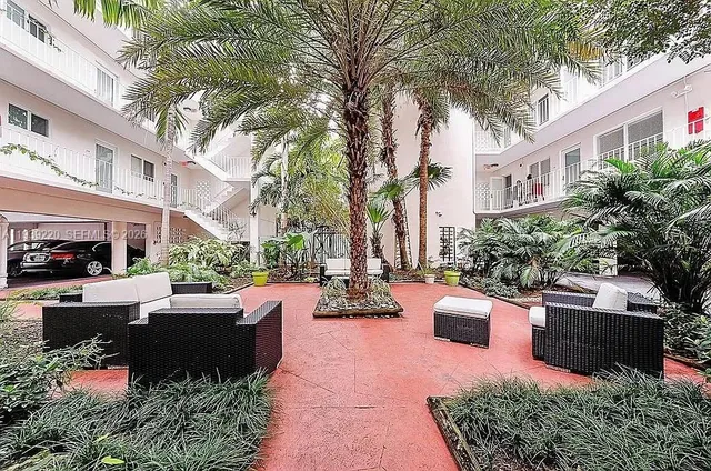a view of a patio with couches table and chairs potted plants and large tree