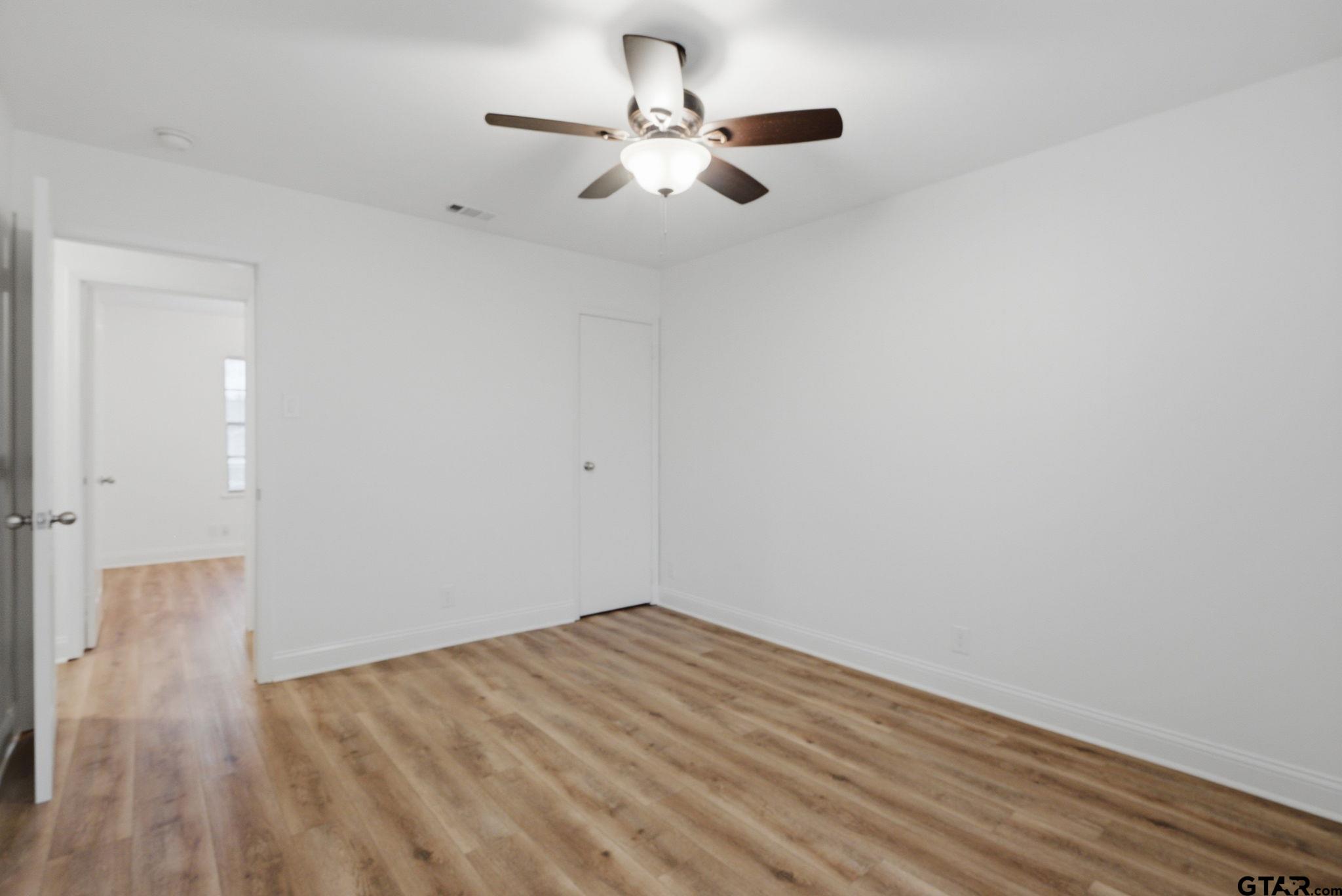 2716 Manilee Lane Tyler, TX 75702 - Photo 10 of 20 an empty room with wooden floor and a ceiling fan