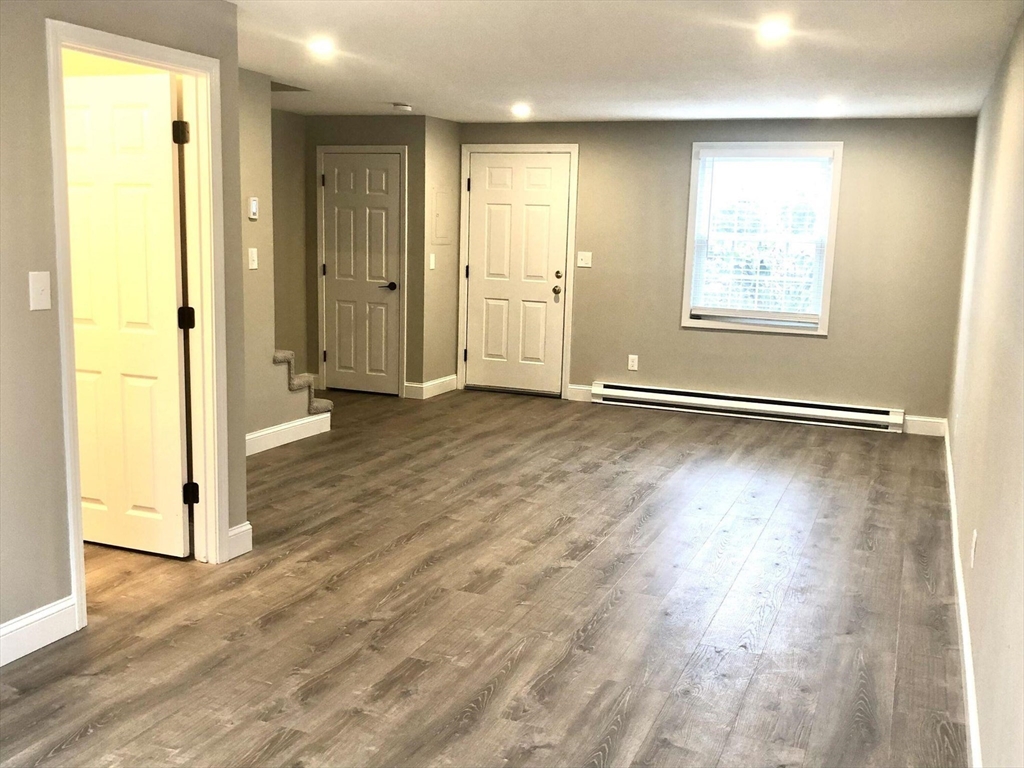 135 West Main Street, Unit 26 Barnstable, MA 02601 - Photo 2 of 11 an empty room with wooden floor mirror and windows