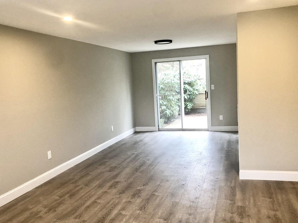 135 West Main Street, Unit 26 Barnstable, MA 02601 - Photo 3 of 11 an empty room with wooden floor and windows