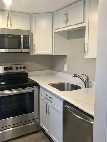 a kitchen with granite countertop a stove top oven microwave and cabinets