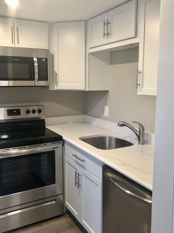 135 West Main Street, Unit 26 Barnstable, MA 02601 - Photo 5 of 11 a kitchen with granite countertop a stove top oven microwave and cabinets