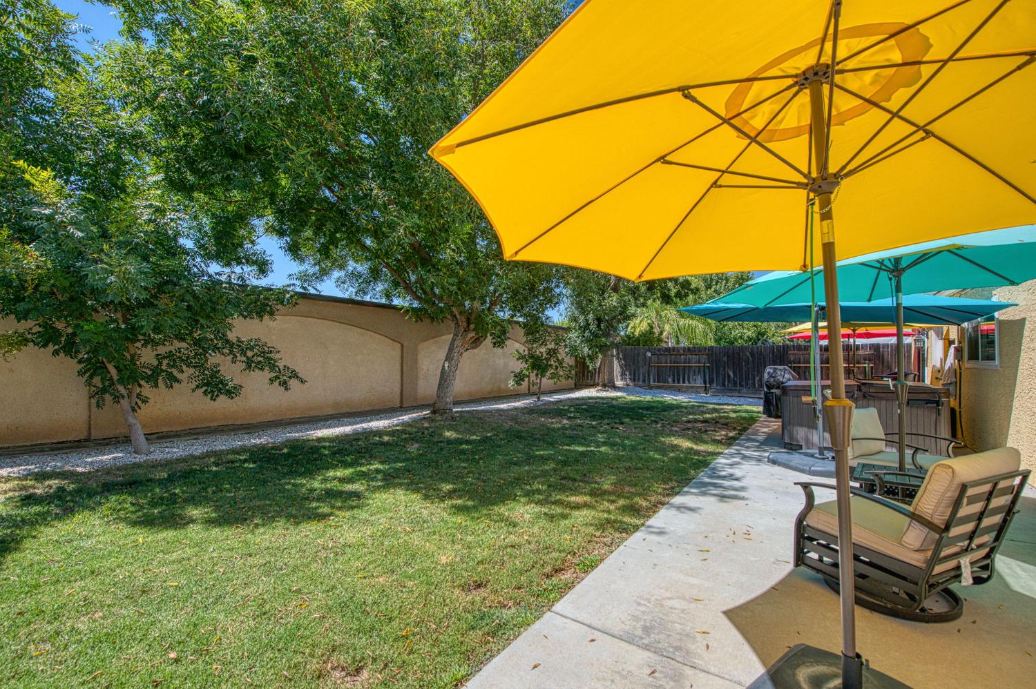 980 North Adler Avenue Clovis, CA 93611 - Photo 33 of 42 a backyard of a house with table and chairs under an umbrella