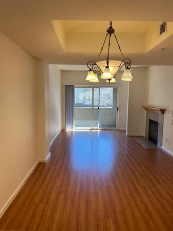 an empty room with wooden floor fireplace and windows