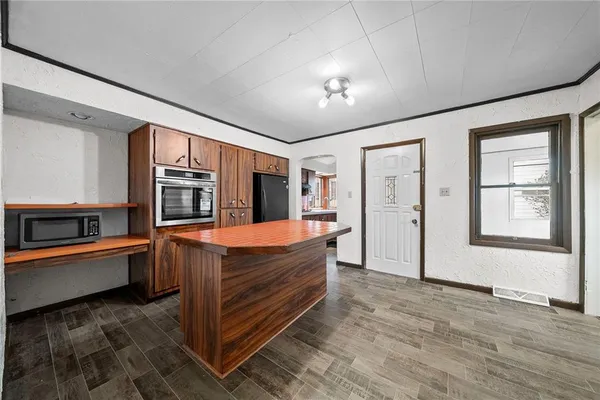 a view of living room kitchen with stainless steel appliances wooden floor and window