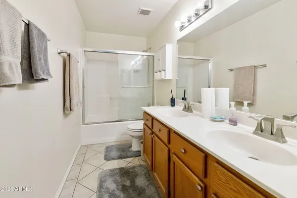a spacious bathroom with a double vanity sink toilet mirror and bathtub
