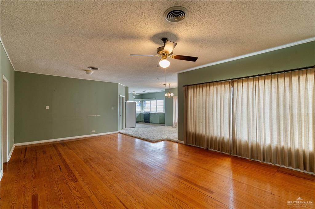 2351 Liberty Street Mercedes, TX 78570 - Photo 6 of 13 Empty room featuring ceiling fan with notable chandelier, a textured ceiling, and hardwood / wood-style flooring