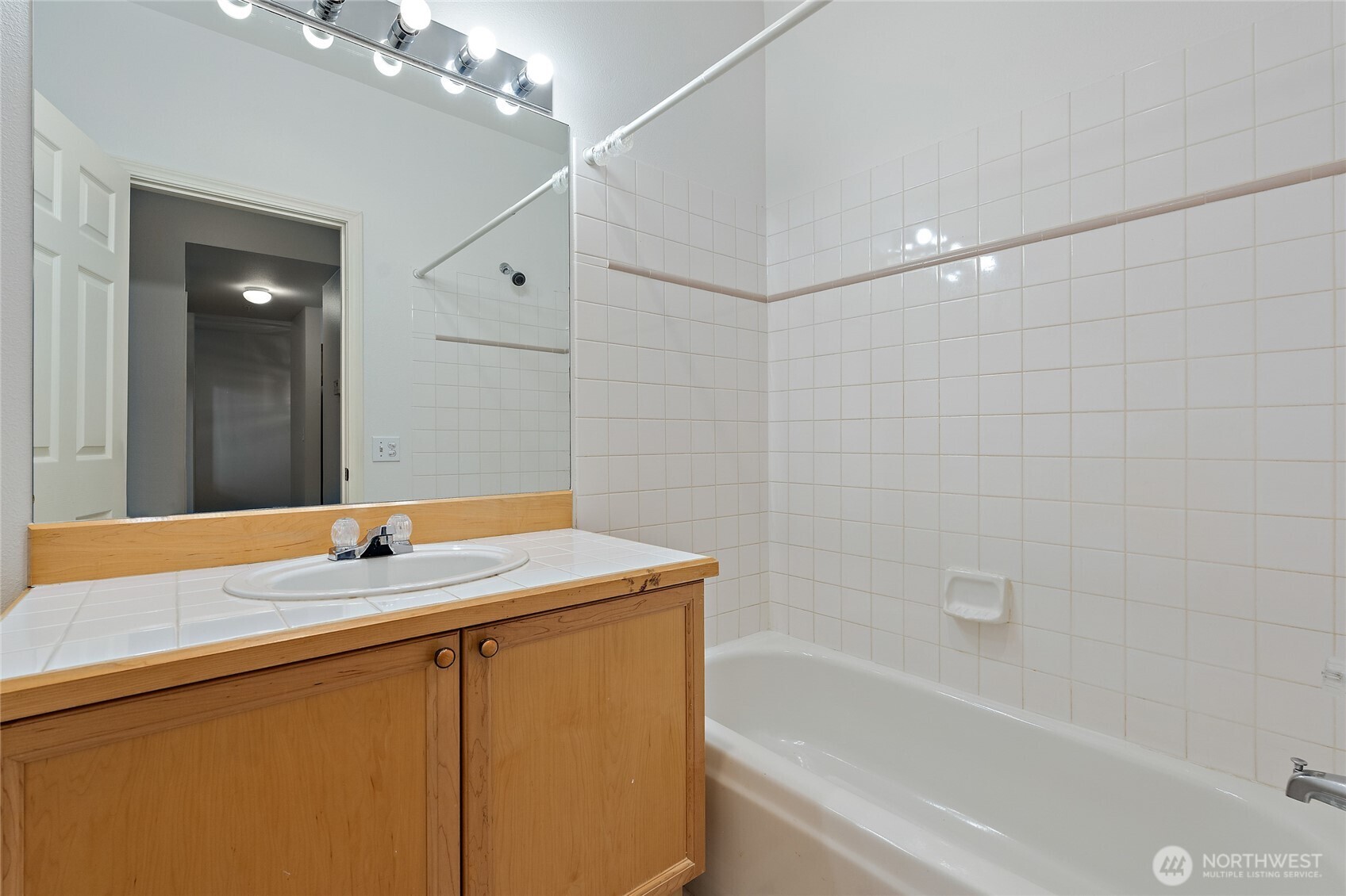 12122 Northeast 171st Place, Unit D201 Bothell, WA 98011 - Photo 28 of 33 a bathroom with a granite countertop sink a toilet a mirror and bathtub