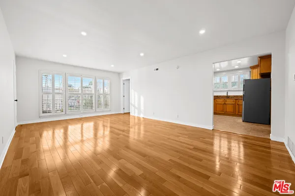 a view of empty room with wooden floor and a window