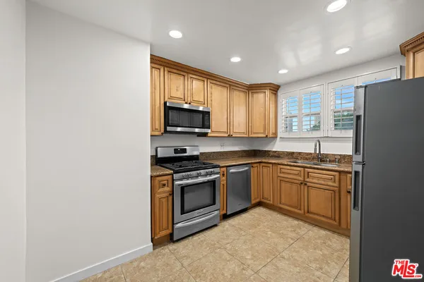 a kitchen with stainless steel appliances granite countertop a stove a sink and a refrigerator