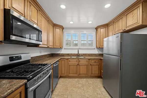a kitchen with stainless steel appliances granite countertop a refrigerator a sink dishwasher a stove and a microwave oven with granite countertops