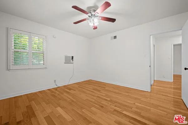 a view of a big room with wooden floor and a chandelier fan