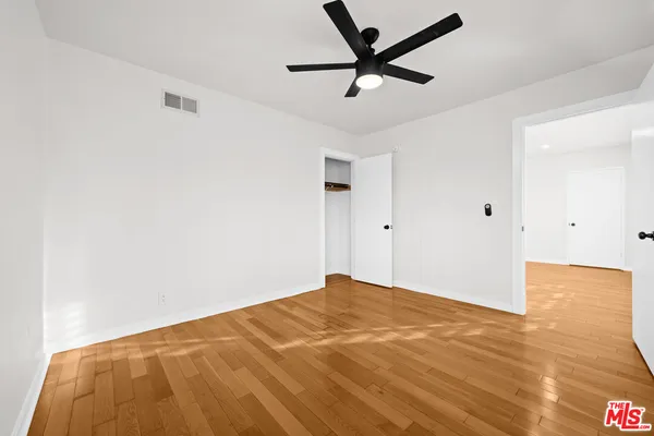 a view of a big room with wooden floor and a ceiling fan
