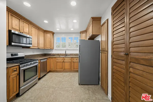 a kitchen with stainless steel appliances granite countertop a refrigerator a stove and a sink