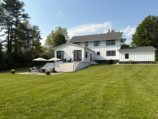 a view of a house with a big yard potted plants and large tree