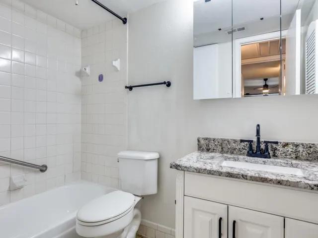 a bathroom with a granite countertop sink a toilet and mirror