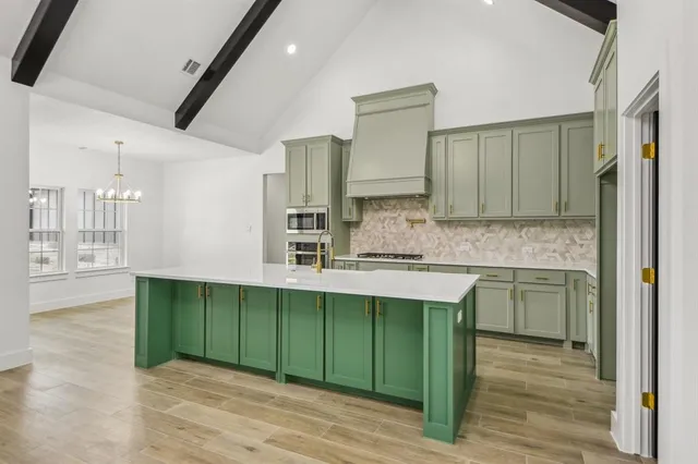 a view of a kitchen with kitchen island a sink wooden floor and a large window