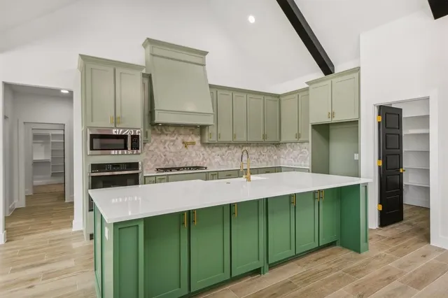 a kitchen with kitchen island granite countertop a sink cabinets and wooden floor