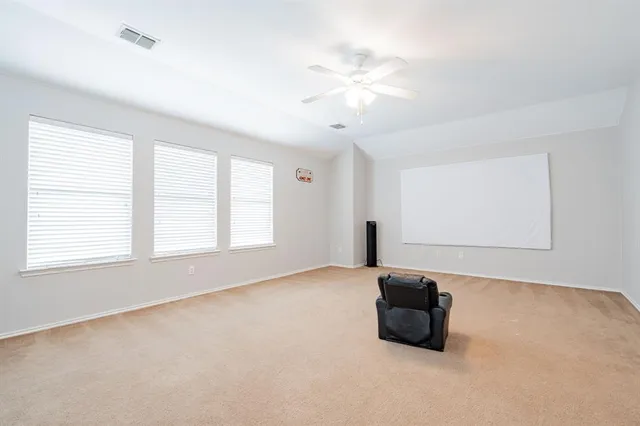 an empty room with windows and fan