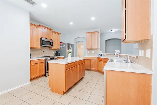 a large kitchen with stainless steel appliances granite countertop a sink stove refrigerator and cabinets
